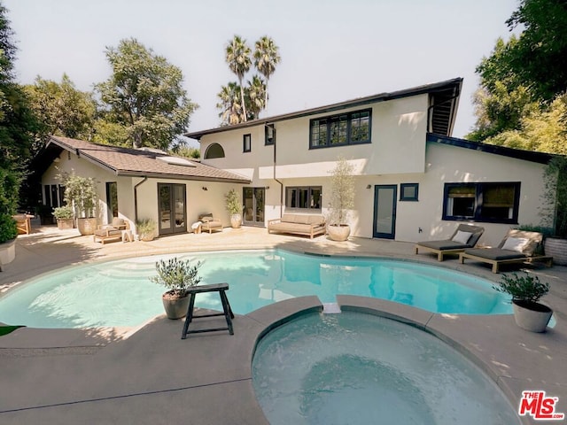 back of property with a pool with hot tub and a patio area