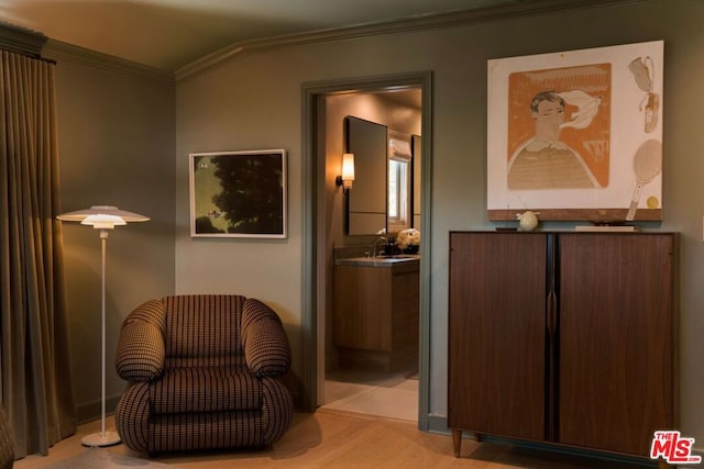 sitting room featuring light hardwood / wood-style floors, vaulted ceiling, crown molding, and sink