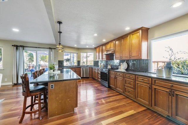 kitchen with pendant lighting, a center island, stainless steel appliances, sink, and a breakfast bar area