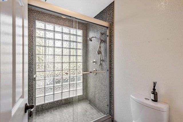 bathroom featuring a shower with shower door and toilet