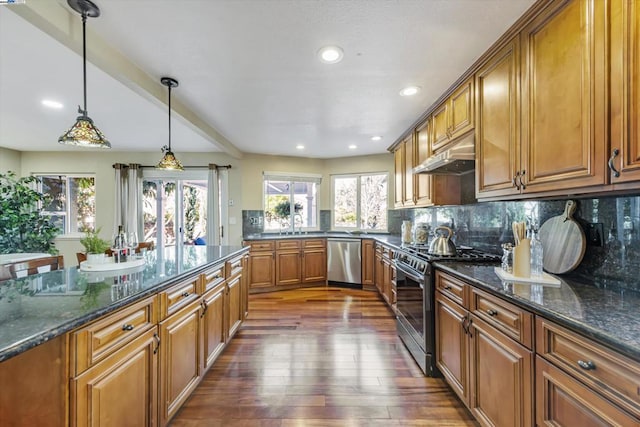 kitchen featuring stainless steel appliances, decorative backsplash, dark hardwood / wood-style floors, hanging light fixtures, and dark stone counters