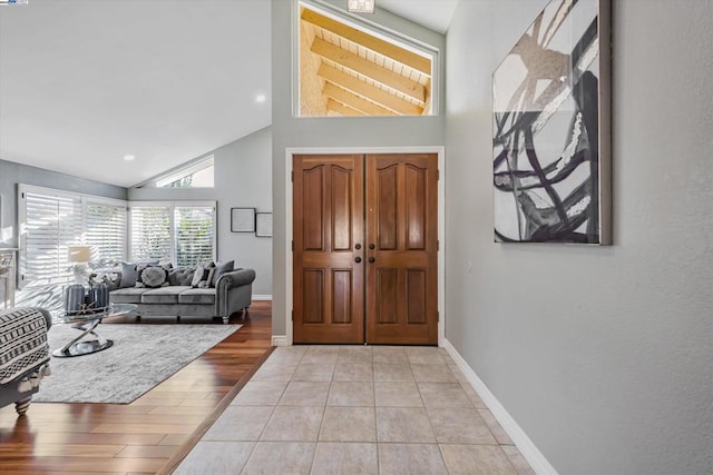 foyer entrance featuring high vaulted ceiling and light tile patterned floors