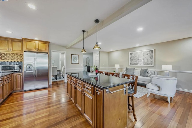 kitchen featuring backsplash, a center island, beam ceiling, hanging light fixtures, and appliances with stainless steel finishes