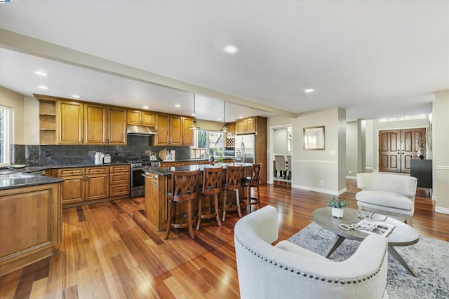 kitchen featuring stainless steel appliances, dark hardwood / wood-style floors, tasteful backsplash, decorative light fixtures, and a kitchen island