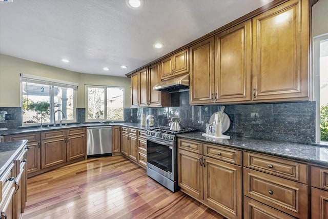 kitchen with decorative backsplash, sink, stainless steel appliances, and dark stone counters