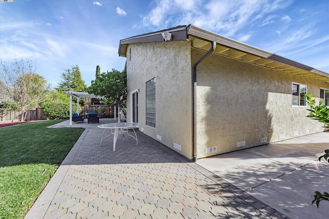 view of side of home featuring a pergola, a lawn, and a patio