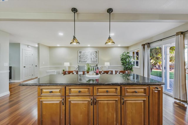 kitchen with dark wood-type flooring, a kitchen island, and pendant lighting