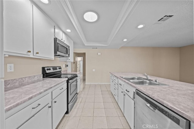 kitchen with a raised ceiling, appliances with stainless steel finishes, light tile patterned floors, white cabinets, and sink