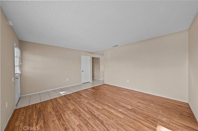 empty room with a textured ceiling and light wood-type flooring