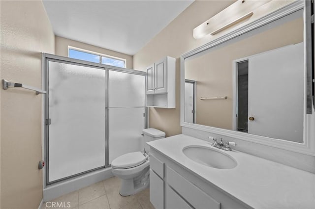 bathroom with toilet, vanity, tile patterned floors, and a shower with shower door