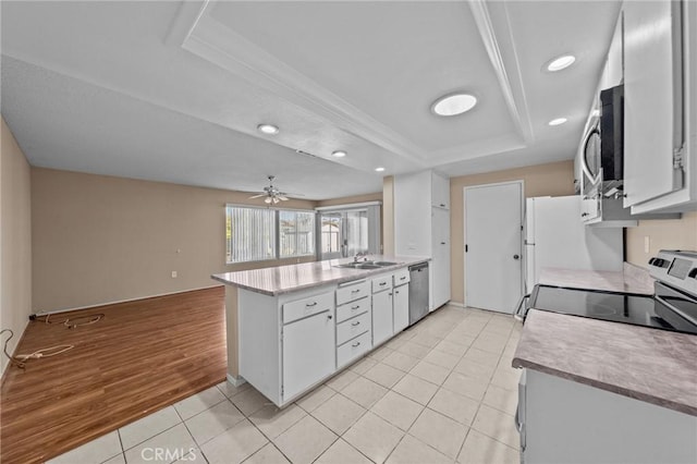 kitchen with a raised ceiling, appliances with stainless steel finishes, light tile patterned floors, ceiling fan, and white cabinets