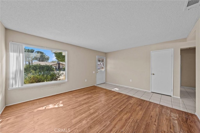 empty room with light hardwood / wood-style floors and a textured ceiling