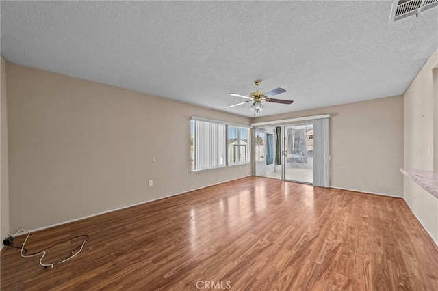 empty room featuring ceiling fan, a textured ceiling, and wood-type flooring