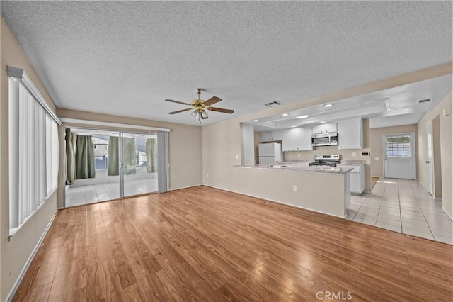 unfurnished living room featuring light wood-type flooring, ceiling fan, and a textured ceiling