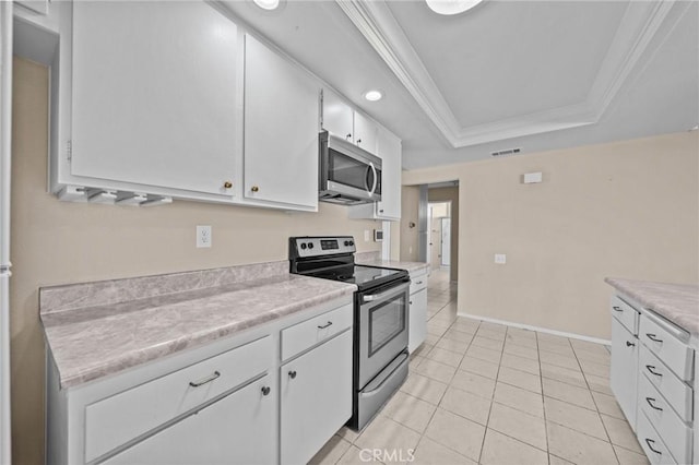 kitchen with white cabinetry, ornamental molding, light tile patterned floors, a tray ceiling, and appliances with stainless steel finishes