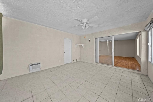 unfurnished room featuring ceiling fan, a wall mounted AC, a healthy amount of sunlight, and a textured ceiling