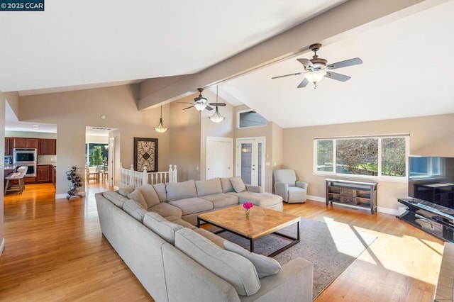 living room featuring light hardwood / wood-style flooring, a healthy amount of sunlight, and vaulted ceiling with beams