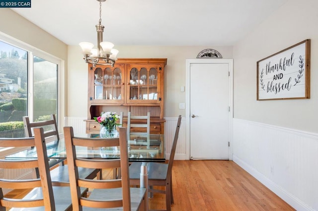 dining space with light hardwood / wood-style floors and a chandelier