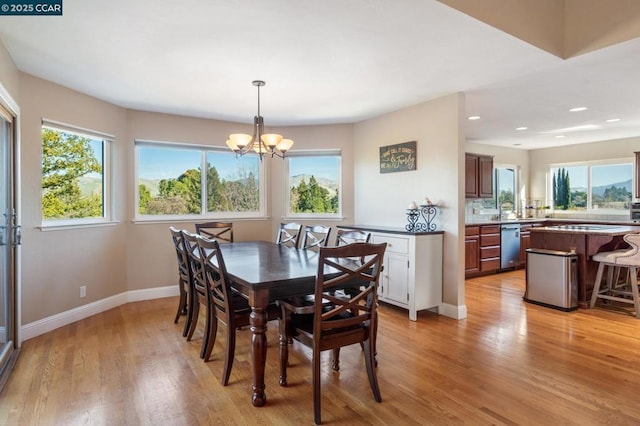 dining room featuring sink, light hardwood / wood-style flooring, plenty of natural light, and a chandelier