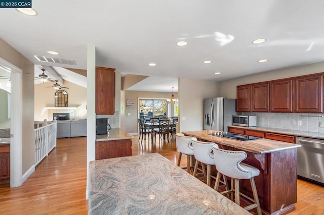 kitchen with a center island, stainless steel appliances, light hardwood / wood-style floors, a breakfast bar, and decorative backsplash