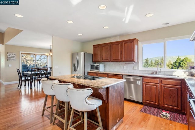 kitchen featuring sink, a center island, light stone counters, a breakfast bar, and appliances with stainless steel finishes