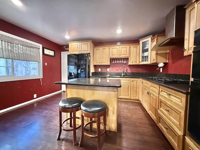 kitchen with a kitchen breakfast bar, dark stone countertops, black appliances, a center island, and wall chimney exhaust hood