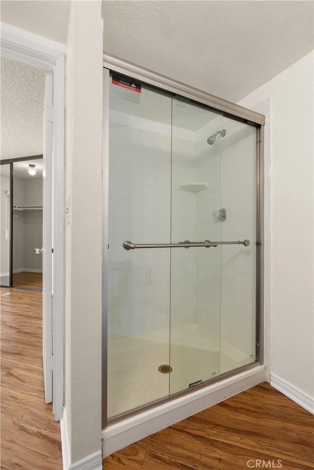 bathroom featuring hardwood / wood-style floors, a textured ceiling, and a shower with shower door