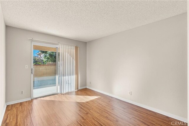 unfurnished room with hardwood / wood-style floors and a textured ceiling