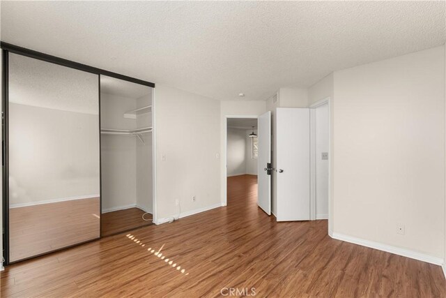 unfurnished bedroom featuring a closet, hardwood / wood-style floors, and a textured ceiling