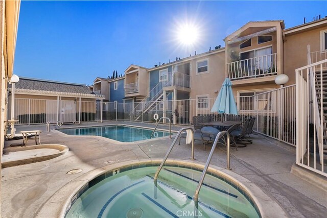 view of swimming pool featuring a hot tub and a patio