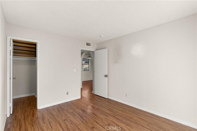 unfurnished bedroom with wood-type flooring, a closet, and a walk in closet