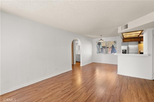 unfurnished living room featuring hardwood / wood-style flooring and a textured ceiling