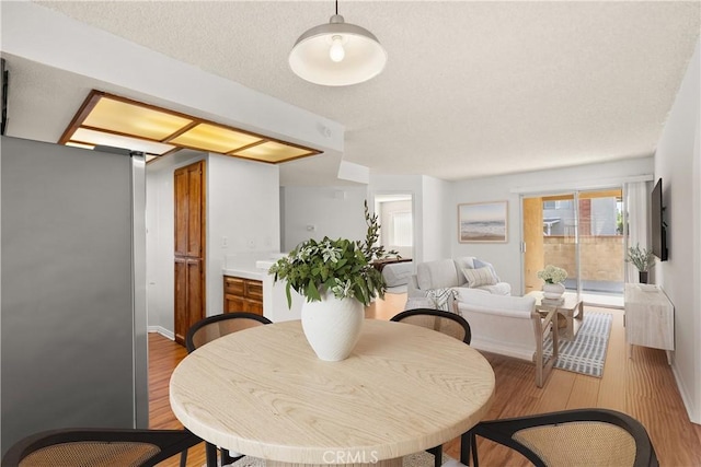 dining area with a textured ceiling and light wood-type flooring