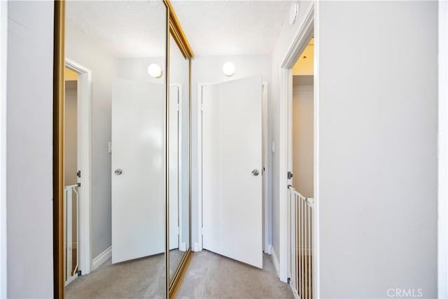 hallway featuring a textured ceiling and light colored carpet