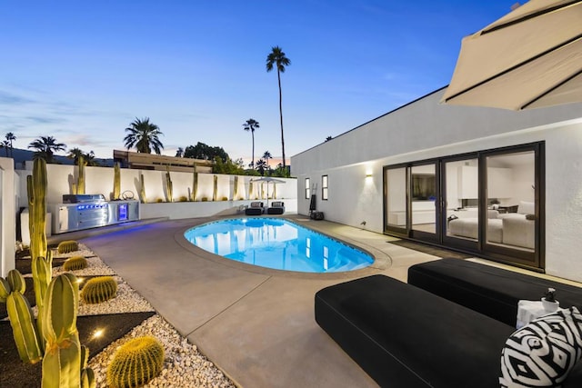 pool at dusk featuring a patio