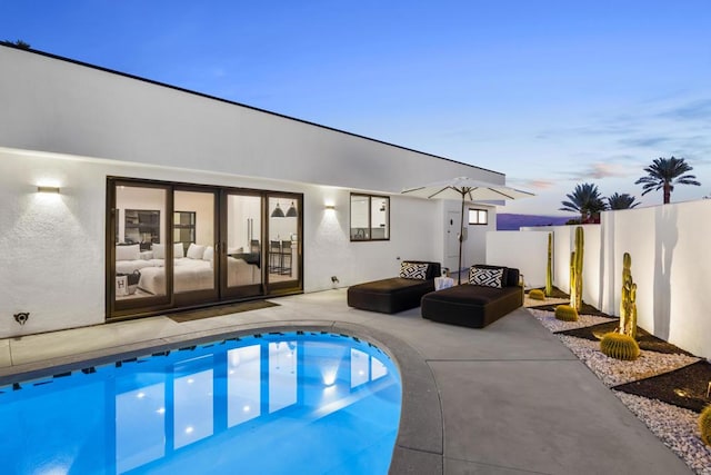 pool at dusk with a patio area