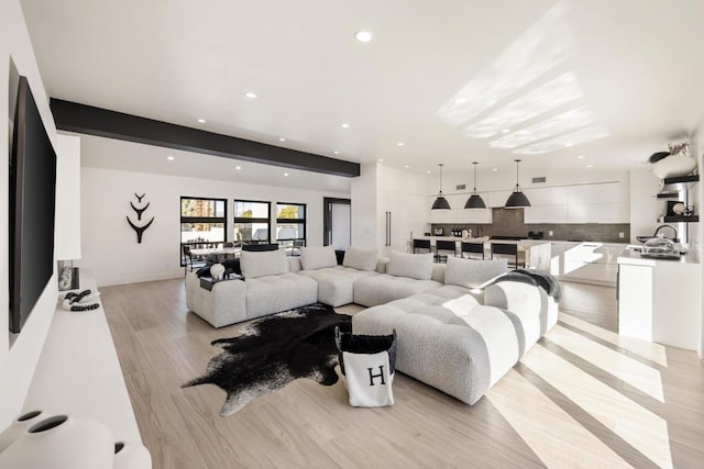 living room with beamed ceiling and light hardwood / wood-style floors