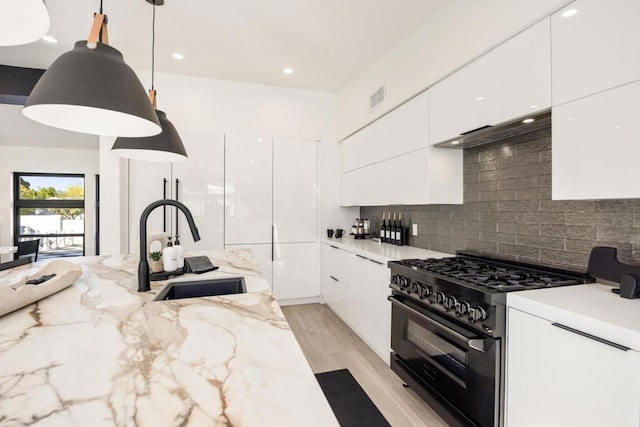 kitchen with decorative light fixtures, sink, white cabinetry, and high end stove