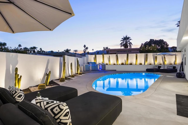 pool at dusk featuring a patio and area for grilling