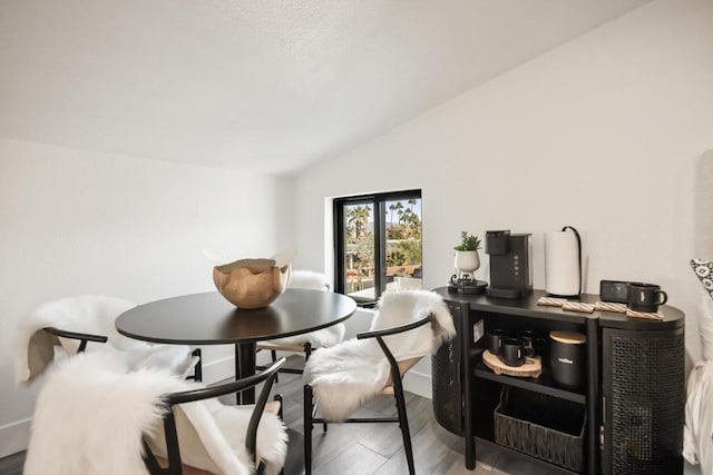 dining space with wood-type flooring and vaulted ceiling