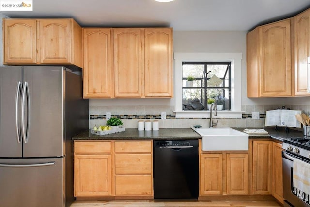 kitchen with appliances with stainless steel finishes, dark stone counters, decorative backsplash, light brown cabinets, and sink