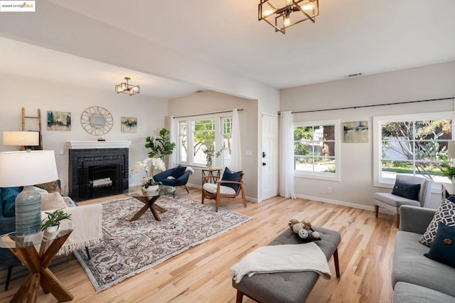 living room with a healthy amount of sunlight, a fireplace, a chandelier, and hardwood / wood-style flooring