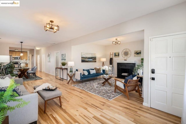 living room with light wood-type flooring and an inviting chandelier