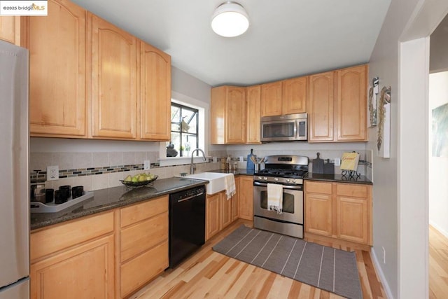 kitchen with appliances with stainless steel finishes, light wood-type flooring, light brown cabinetry, and sink