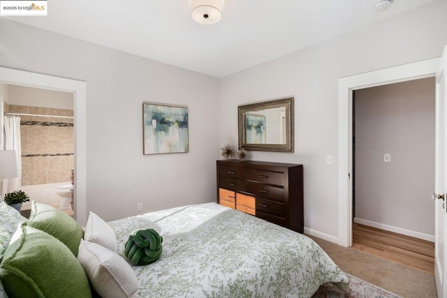 bedroom with ensuite bathroom and carpet flooring