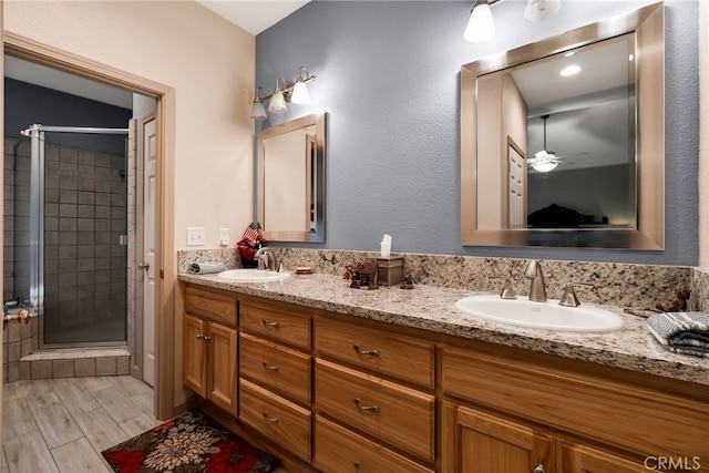 bathroom with ceiling fan, a shower with shower door, and vanity