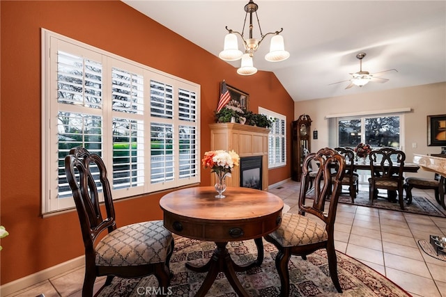 dining space featuring lofted ceiling, light tile patterned flooring, and ceiling fan with notable chandelier