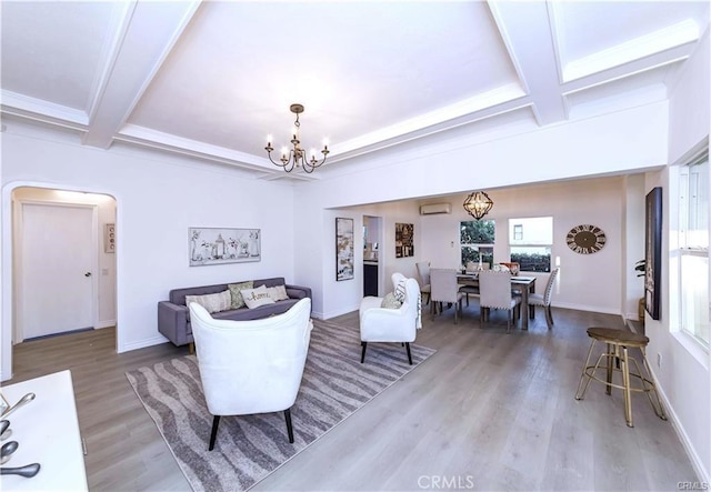 living room featuring a notable chandelier, a wall unit AC, hardwood / wood-style floors, beamed ceiling, and coffered ceiling