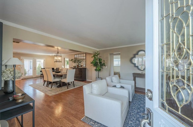 living room featuring hardwood / wood-style flooring, a notable chandelier, and crown molding