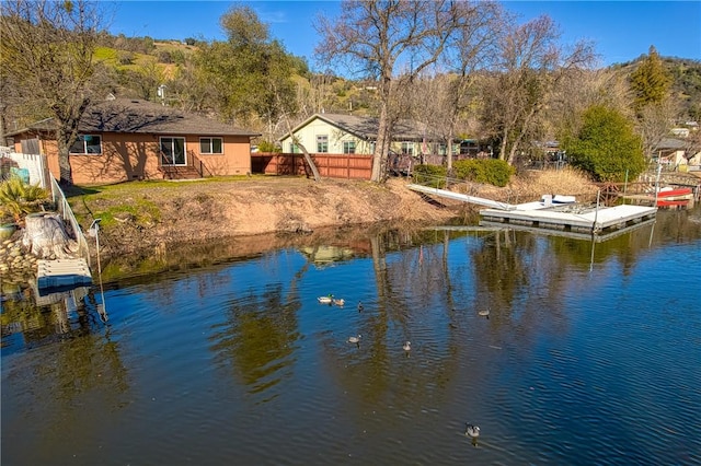 view of water feature with entry steps, a boat dock, and fence